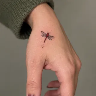 Small red dragonfly fine line hand tattoo