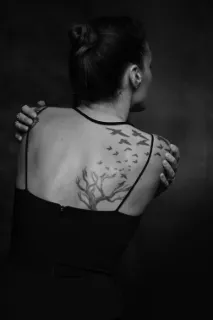 Blackwork tree and flock of birds upper back tattoo