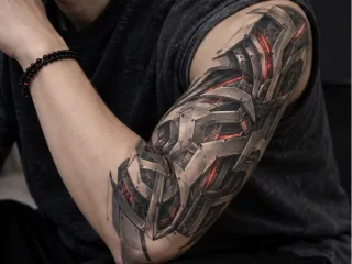 Biomechanical metallic armor upper arm tattoo with red glowing accents