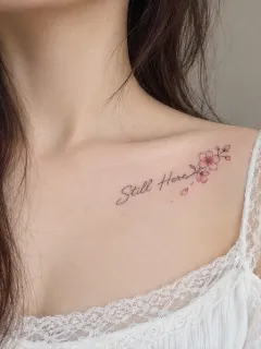 Fine line still here script and flower collarbone tattoo