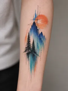 Watercolor mountain and pine tree landscape forearm tattoo