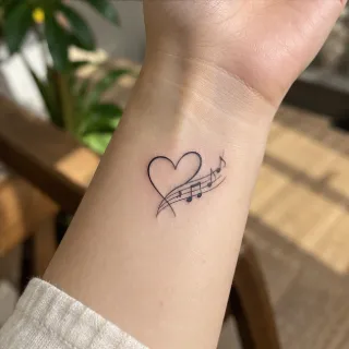 Minimalist fine line heart and musical notes wrist tattoo