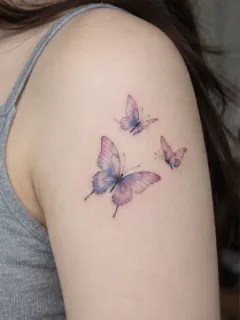 Watercolor style three butterflies upper arm tattoo