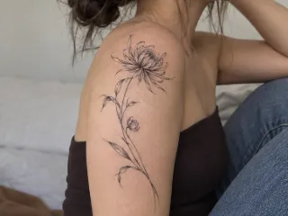 Fine line chrysanthemum flower upper arm tattoo