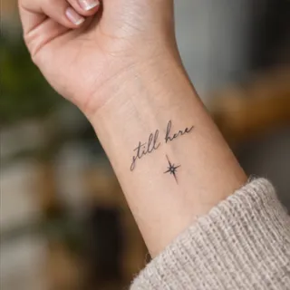 Fine line still here script and star wrist tattoo