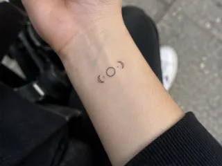 Minimalist fine line moon phases wrist tattoo