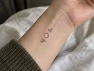 Minimalist fine line circle and wave symbols wrist tattoo