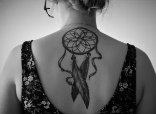Blackwork dreamcatcher with feathers upper back tattoo