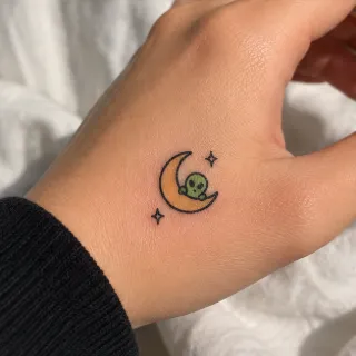 Small minimalist alien and crescent moon hand tattoo