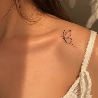 Minimalist fine line butterfly collarbone tattoo