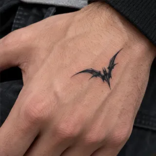 Small blackwork bat silhouette hand tattoo