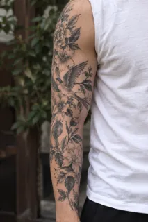 Black and grey bird and floral sleeve tattoo