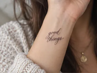 Fine line cursive script good things wrist tattoo