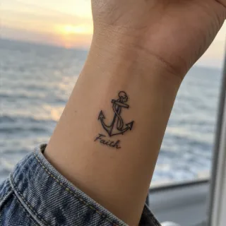 Small fine line anchor and faith script wrist tattoo