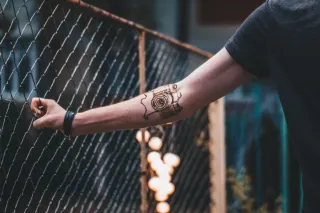 Detailed camera line art forearm tattoo