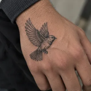 Small flying bird realism style hand tattoo