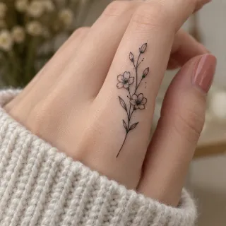 Fine line floral branch finger tattoo